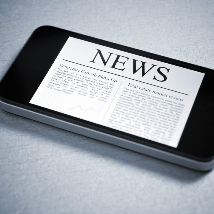 Ein Smartphone zeigt eine digitale Zeitungsansicht mit der Überschrift „NEWS“.